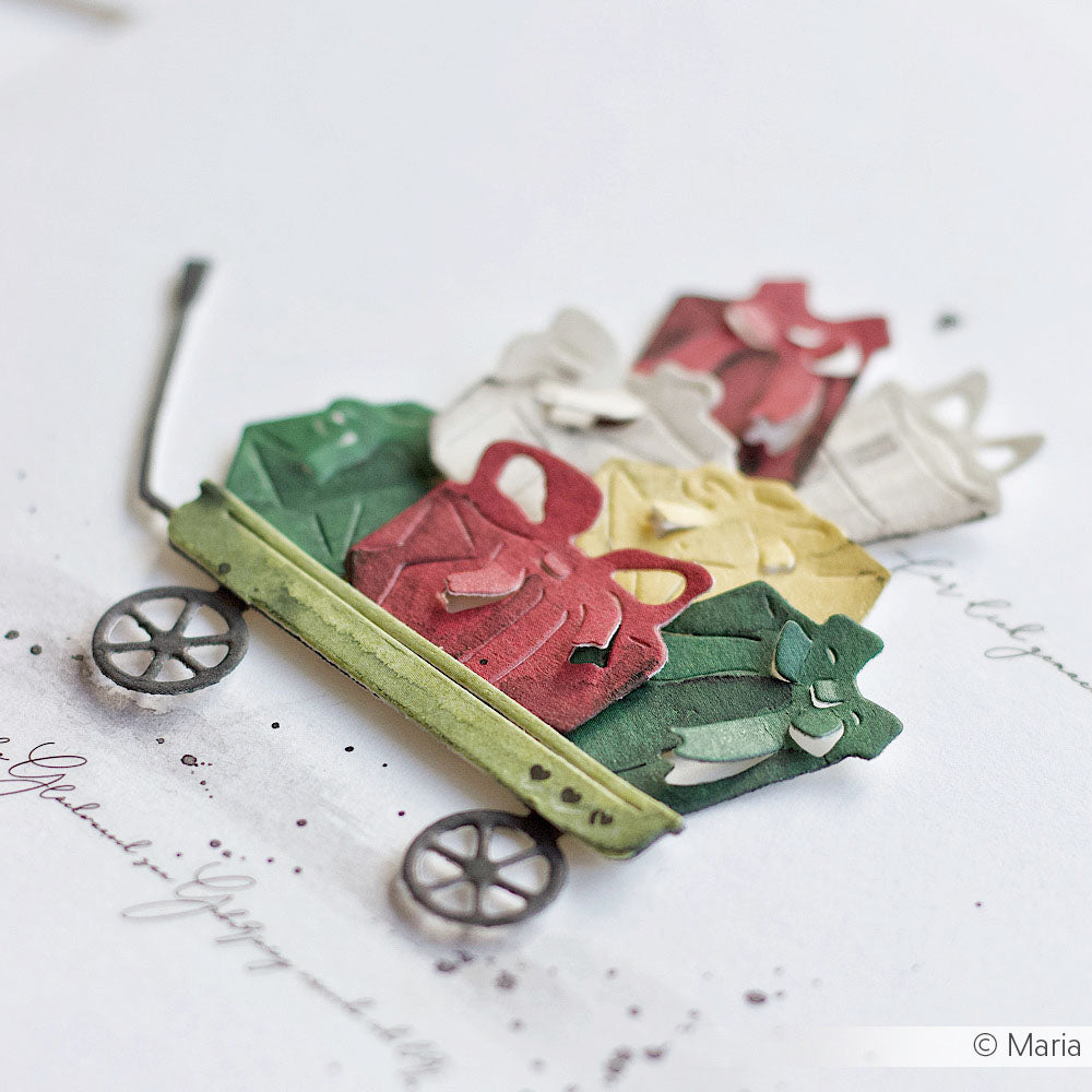 Ein grüner Papierwagen, gefüllt mit bunten Geschenktüten und Geschenken, aus der Vogelperspektive betrachtet - gefertigt mit Alexandra Renke Stanzsystemen und Motivstanzen für entzückende individuelle Details.