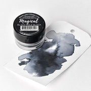 Ein Glas Lindy's Stamp Gang Magical Black Hole Black hochpigmentiertes Pulver steht neben einem Anhänger mit einem dunkelschwarzen Aquarell-Farbmischungen-Spritzer.