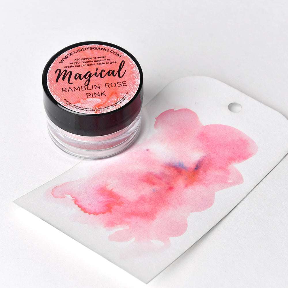 Ein kleines Döschen mit Lindy's Stamp Gang Ramblin Rose Pink Zauberpulver steht neben einem Anhänger mit einem rosa Aquarellfleck.