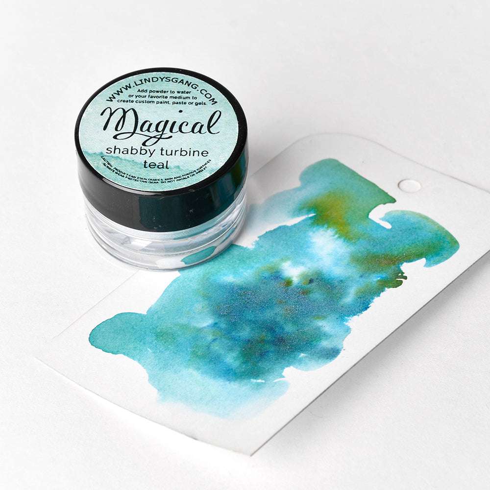 Eine Dose Lindy's Stamp Gang hochpigmentiertes Pulver neben einem Anhänger mit blaugrüner Aquarellfarbe - ideal für Farbmischungen und kreative Effekte.