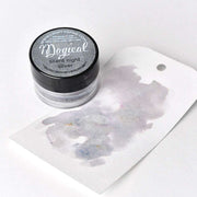 Eine kleine Dose Lindy's Stamp Gang Magical Silent Night Silver High-Pigment-Pulver steht neben einem Anhänger mit einem silbernen Aquarellmuster, perfekt für kreative Farbmischungen.