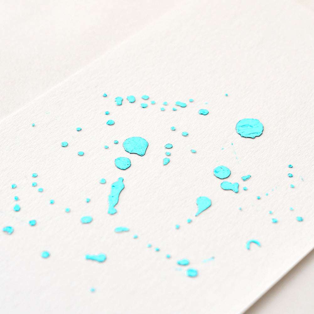 Aquablaue Tinte spritzt über ein weißes Blatt Papier und verleiht dem schlichten Design einen Hauch von ☆ Exklusivität.