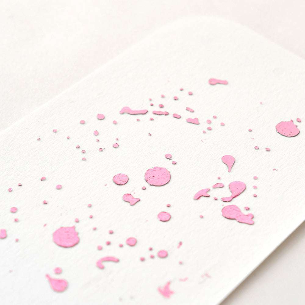 Weiße Karte mit abgerundeten Ecken, verziert mit rosa Farbspritzern und Punkten und veredelt mit Heißfolie Beere für ein edles Finish. Marke: ☆.