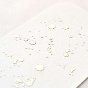 Weißes strukturiertes Papier mit kleinen Goldfolientröpfchen und -flecken bildet ein abstraktes Muster, das die Eleganz und Exklusivität von ☆ durch raffinierte Heißfoliendetails widerspiegelt.