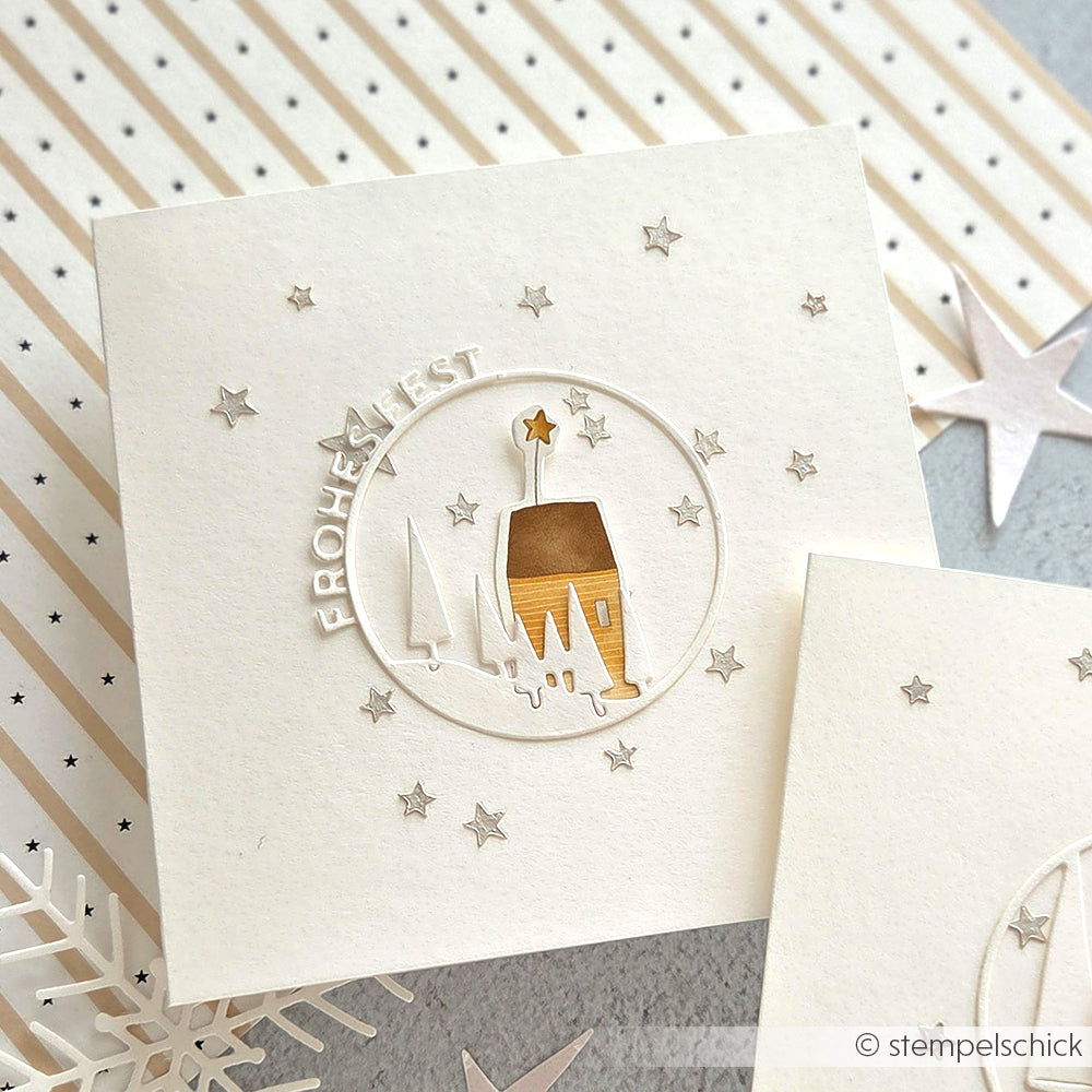 Quadratische Karte von Alexandra Renke mit einer Winterhütte, einem Stern, Bäumen und dem Text "Frohe Fest" mit kleinen Sternen in einem Stencil Sterne Muster - ideal für Schablonen-Projekte oder die Gestaltung wiederverwendbarer Festtagskarten.