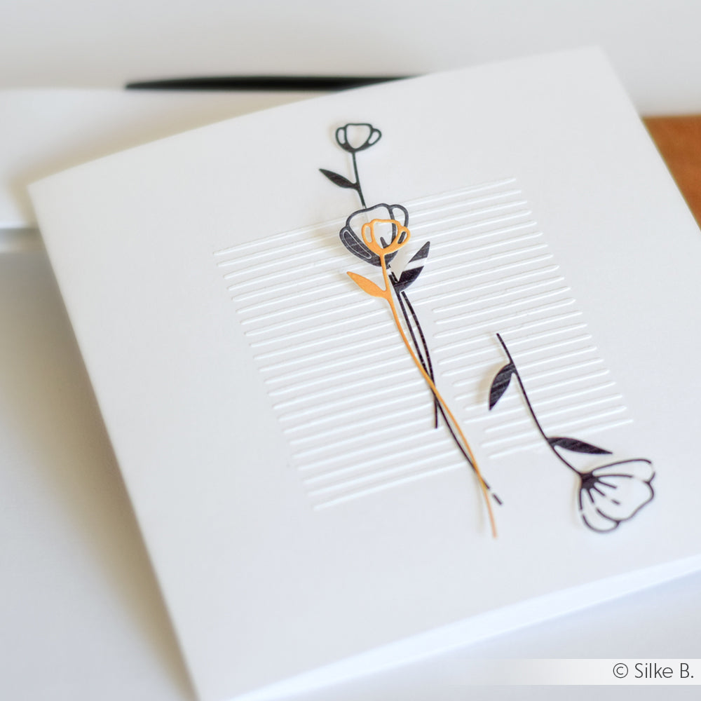 Eine weiße Grußkarte von Alexandra Renke mit einer minimalistischen schwarz-goldenen Blume, geprägten Linien und dezenten Stencil Linienmuster Doppelt-Details - gefertigt mit wiederverwendbaren Schablonen für einen raffinierten, modernen Look.