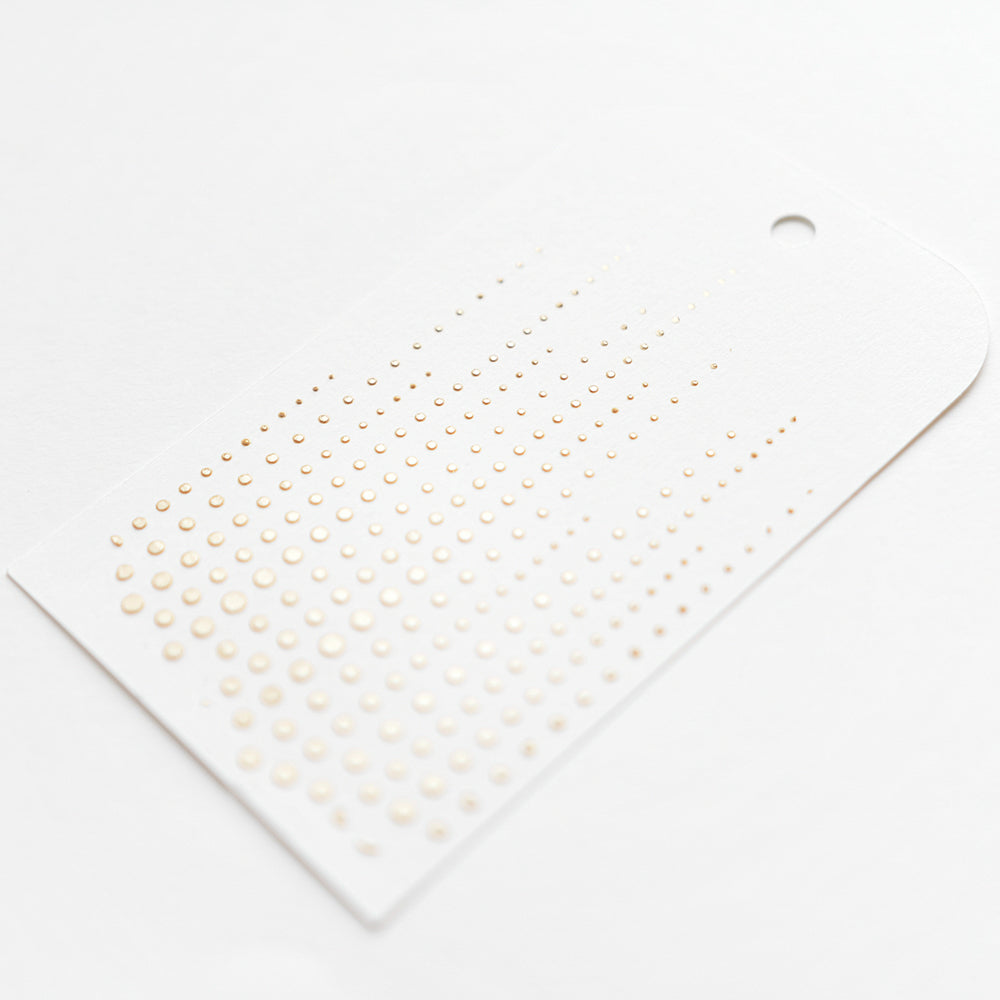 Weißer Anhänger von Alexandra Renke mit Reihen von kleinen goldenen Punkten in einem Farbverlauf, Loch oben rechts - ideal für Papierprojekte oder wiederverwendbare Schablonen wie Stencil Punkteketten.