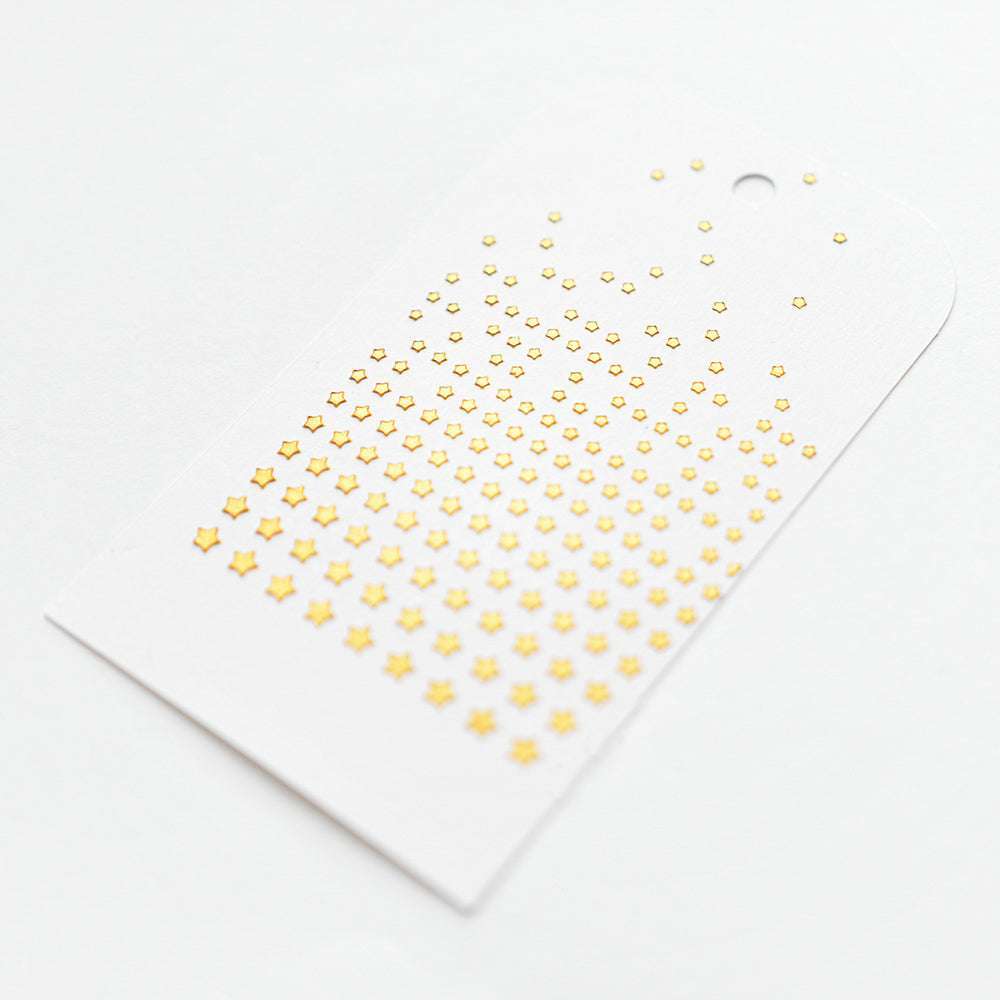 Eine weiße Karte mit Reihen von kleinen goldenen Sternen in einem Farbverlauf, hergestellt mit Alexandra Renke wiederverwendbaren Schablonen und dem Stencil Sternregen Raster für eine präzise Platzierung.