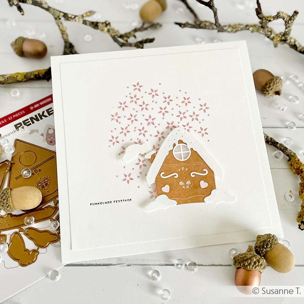 Quadratische Karte von Alexandra Renke mit einem Lebkuchenhaus, rosa Herzkonfetti, Eicheln und Zweigen - ideal, um mit wiederverwendbaren Schablonen oder Sternen Stencil Formen kreative Weihnachtsakzente zu setzen.