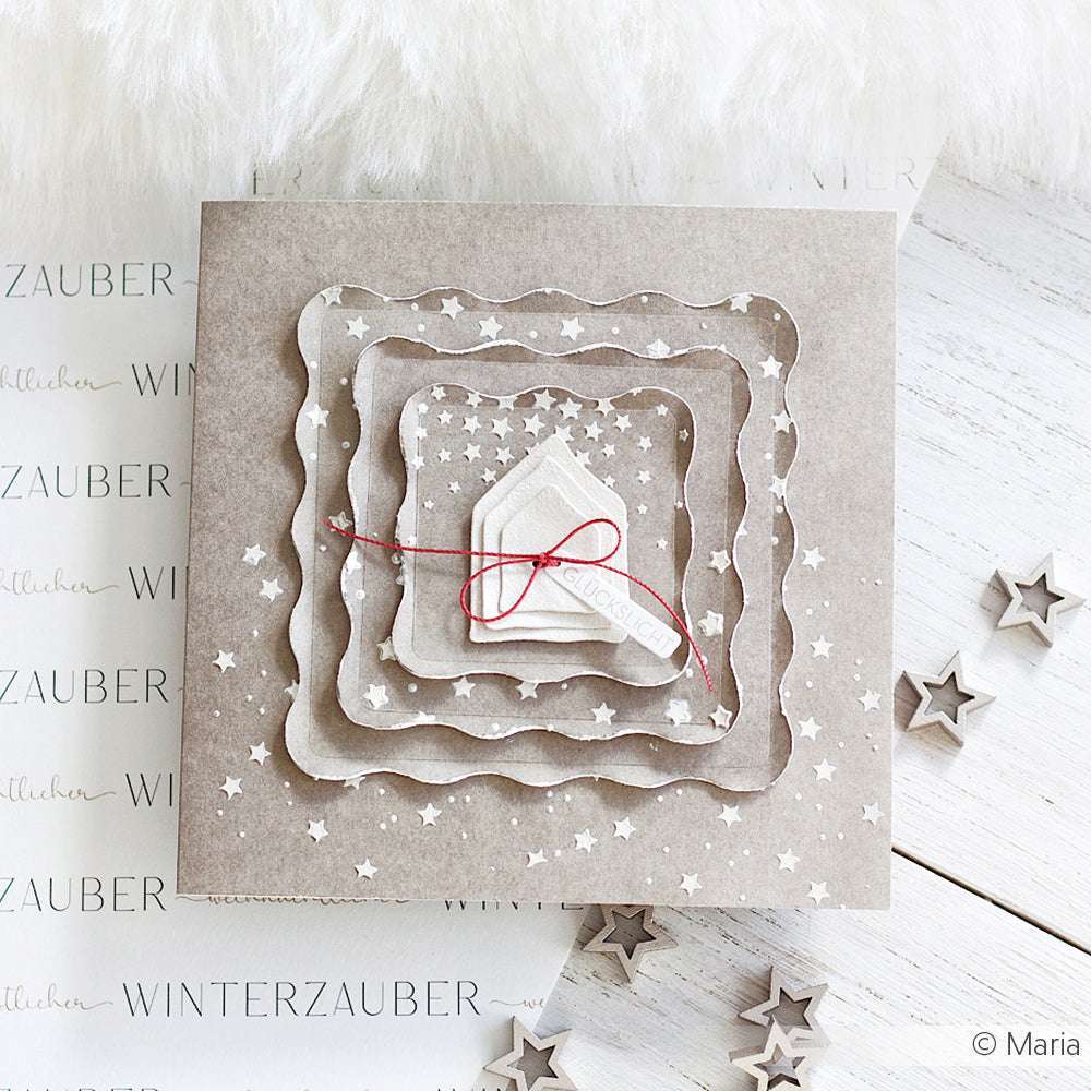 Quadratische Karte mit geschichteten Sternausschnitten, die mit Schablonen von Alexandra Renke hergestellt wurden, verziert mit einer roten Schleife auf einem winterlichen, neutralen Hintergrund - ein reizvolles, saisonales Papierprojekt.