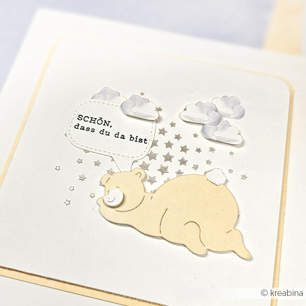 Ein lächelnder Cartoon-Bär mit der Sprechblase "SCHÖN, dass du da bist", umgeben von Sternen und Wolken, gestaltet mit wiederverwendbaren Alexandra Renke Schablonen und Sternschablonen.