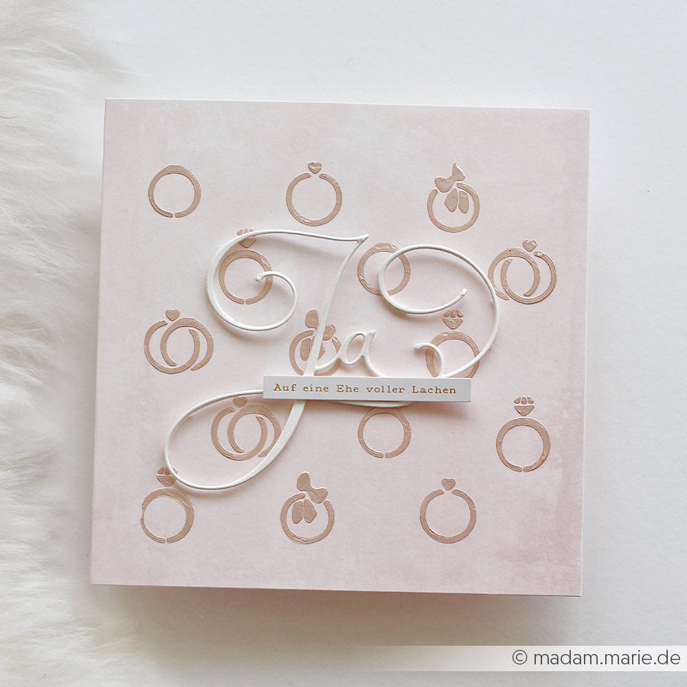 Quadratische Karte von Alexandra Renke mit "Ja" und "Auf eine Ehe voller Lachen" auf rosa, mit Ring-Illustrationen - ideal zum Basteln mit wiederverwendbaren Schablonen oder zum Hinzufügen Ihrer eigenen Stencil Ringfreude.