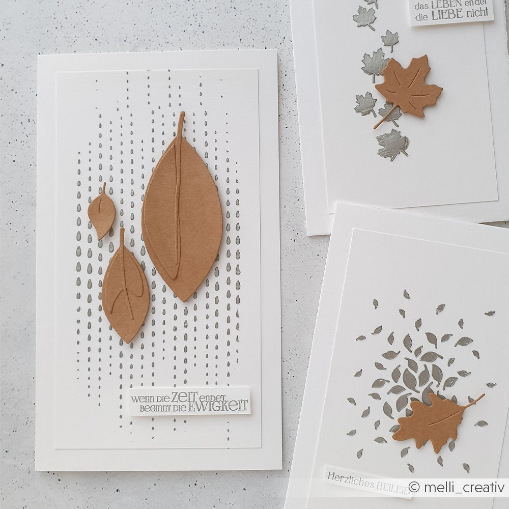 Drei handgefertigte Karten mit braunen und grauen Blattmotiven und deutschem Text, angeordnet auf einem hellen Hintergrund. Jede Karte besticht durch filigrane Details, die mit Schablonen von Papierprojekte und wiederverwendbaren Schablonen gestaltet wurden, darunter das einzigartige Schablonenmuster „Tropfenketten“.