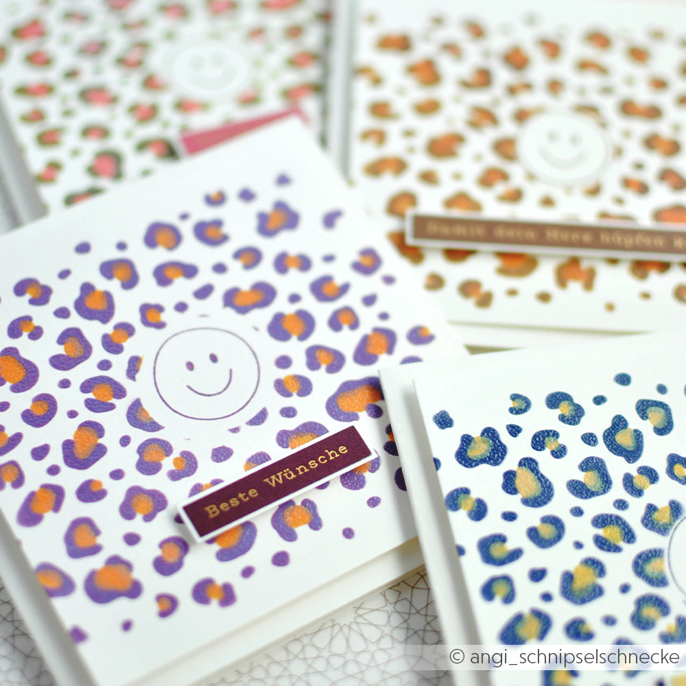 Handgefertigte Karten mit farbenfrohen Schablonenmotiven im Geschichteten Leoparden-Print – mit leuchtenden Leopardenflecken, Smileys und deutschen Grußtexten – sind dicht nebeneinander ausgestellt. Diese Karten eignen sich perfekt für Ihre Schablonen-Papierprojekte und sind wunderschön gestaltet – dank wiederverwendbarer Schablonen entstehen jedes Mal einzigartige Designs.