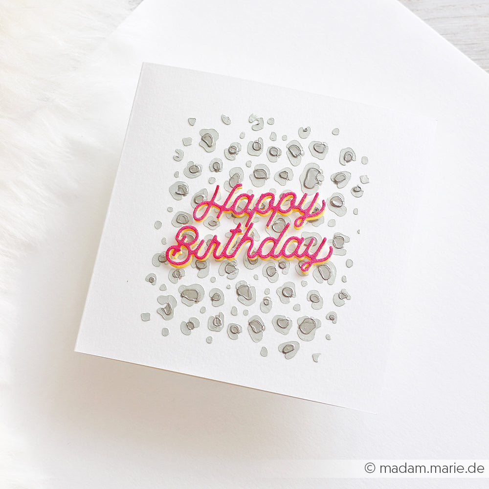 Quadratische Karte mit der Aufschrift „Happy Birthday“ in Rosa auf einem grauen, geschichteten Leopardenmuster, platziert auf einem weißen Hintergrund – die perfekte Inspiration für Schablonen-Papierprojekte oder für alle, die nach wiederverwendbaren Schablonen für kreative Grußkarten suchen.