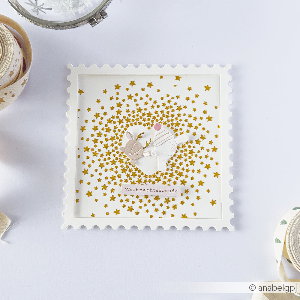 Quadratische Karte in Briefmarkenform mit goldenen Sternen, einem Reh und einem Kaninchen für Schablonenprojekte.