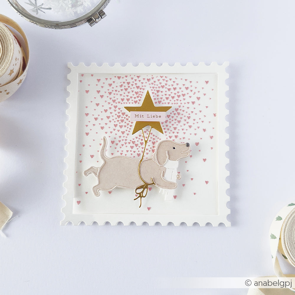 Eine Briefmarken-Schablonenkarte mit einem Dackel, der einen goldenen Stern mit der Aufschrift Mit Liebe in der Pfote hält.