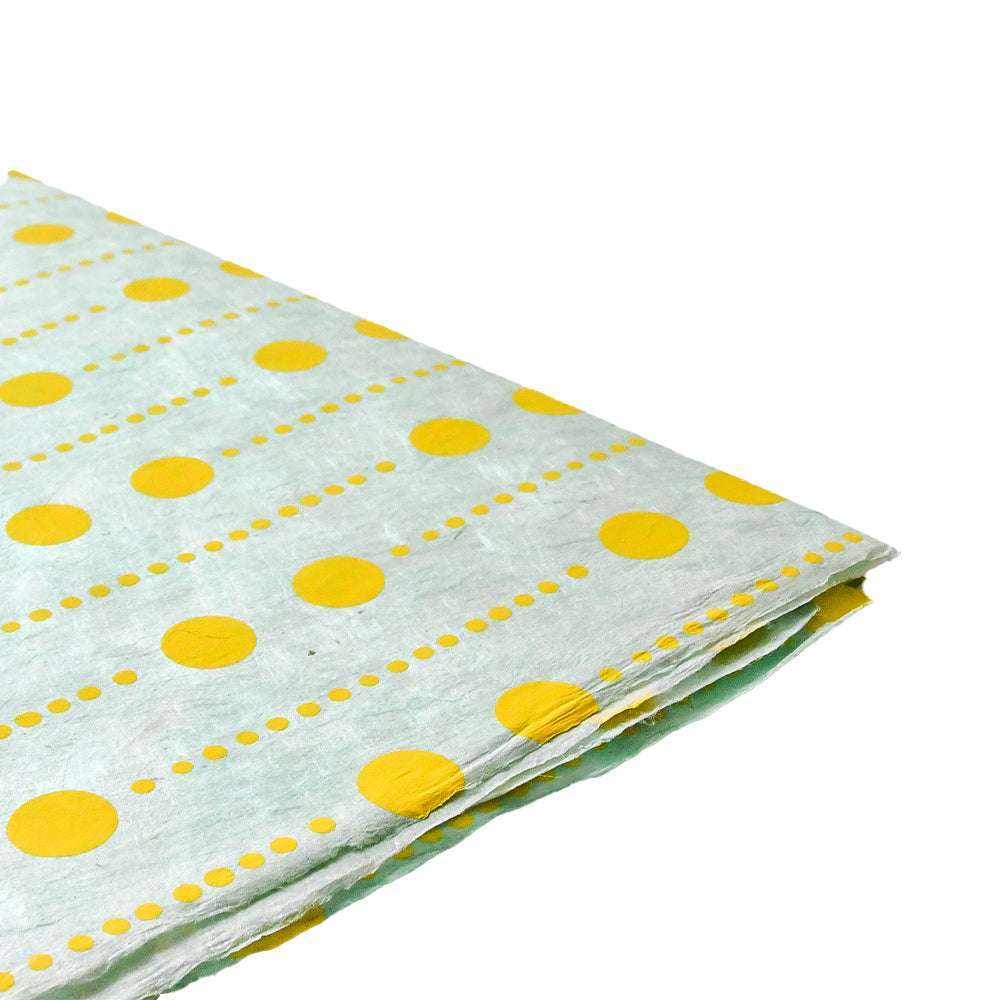 Ein Stapel ☆ weißer Tücher mit gelben Tupfen und gepunkteten Rändern, inspiriert von Nepalpapier - ideal zum Verpacken von Geschenken oder zum Buchbinden.