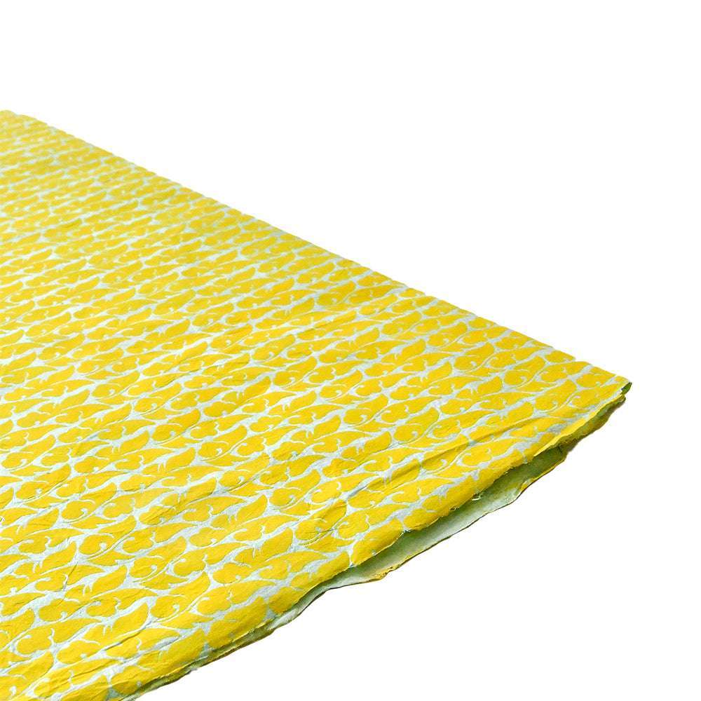 Ein gefaltetes Stück gelbes Nepalpapier von ☆ mit weißem Blumenmuster, ideal zum Buchbinden oder Verpacken von Geschenken, dargestellt vor weißem Hintergrund.
