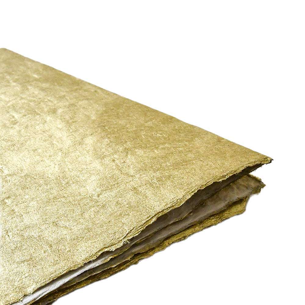 Ein Stapel goldener Fasertücher von ☆, handgefertigt aus Nepalpapier, ideal zum Verpacken von Geschenken, ruht vor einem weißen Hintergrund.