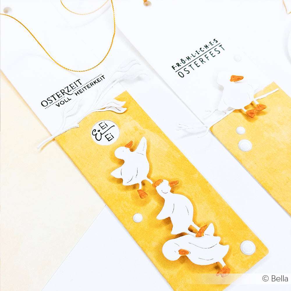 Drei weiße Entenausschnitte zieren gelbe Oster-Lesezeichen mit deutschem Text und Clear Stamp Motiven von Alexandra Renke - festliche Akzente für einzigartige Papierprojekte.