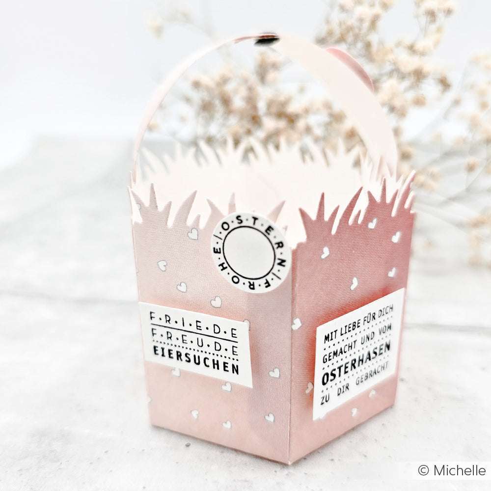 Osterkörbchen aus rosafarbenem Papier von Alexandra Renke mit Herzmustern, einem mit Photopolymer-Stempel gestempelten deutschen Text und einem charmanten Wellenrand.