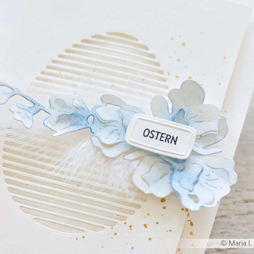 Grußkarte mit einer ausgeschnittenen Eierform, blauen Blumen und einem OSTERN-Etikett in der Mitte. Hergestellt mit Alexandra Renke Photopolymer Stempel für gestochen scharfe Designs - ein perfekter Touch für die kunterbunte Osterzeit.