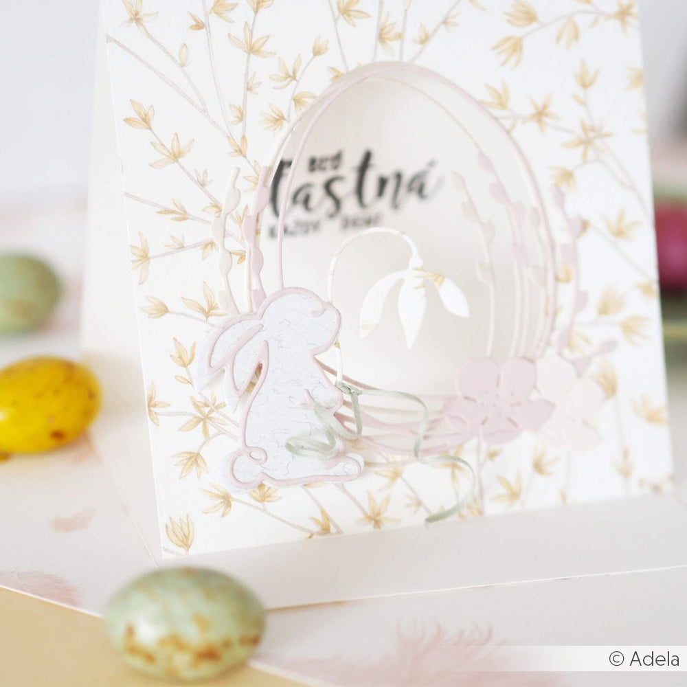 Die Osterkarte von Alexandra Renke zeigt einen Hasen, pastellfarbene Blumen und eine ausgestanzte Eierform mit bunten Bonbons - ideal für die Verwendung von Stanzen aus Stahl oder anderen DieCut Systemen.