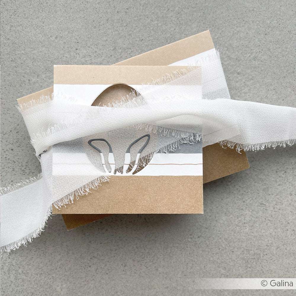 Brauner Umschlag mit weißer Karte mit Hasenohren und ausgefranstem Band - ideal für Alexandra Renke Fans, die Motivstanze Ei mit Hasenohren oder andere Stanzsysteme auf grauem Untergrund verwenden.