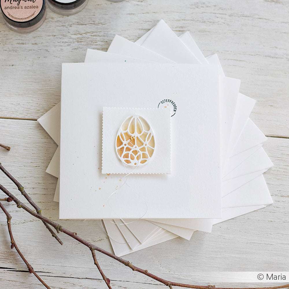 Quadratische weiße Karte von Alexandra Renke mit einem zarten Motivstanze Ornament-Ei-Ausschnitt auf hochwertigen Designpapieren.