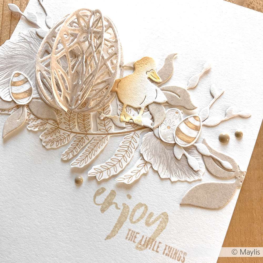 Handgefertigte Karte von Alexandra Renke mit Designpapieren und Scherenschnitten von einem Ei, einer Ente, Blättern, Eiern und dem Text "Enjoy the little things". Mit detaillierten DieCut Systemen und Motivstanze Ornament-Ei für zusätzlichen Charme.