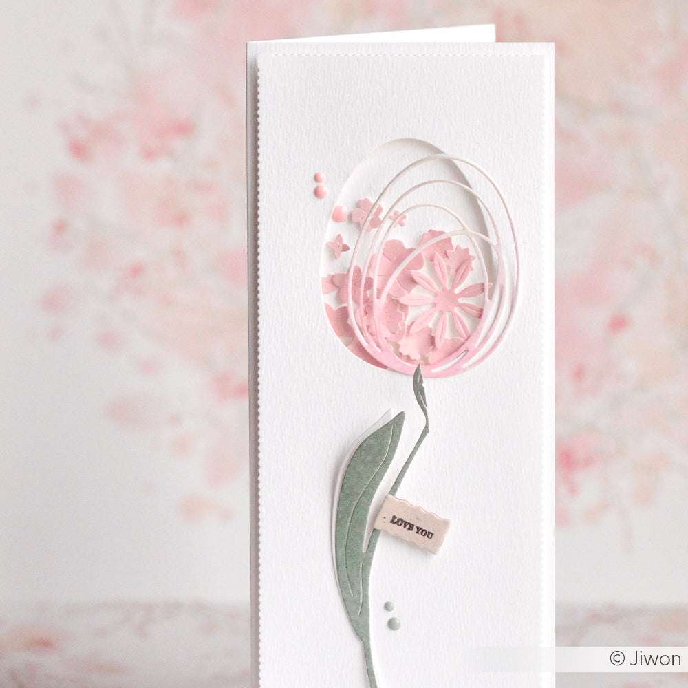 Handgefertigte Karte mit einer zarten rosafarbenen Blume, grünem Stiel und einem kleinen "LOVE YOU"-Anhänger - hergestellt mit Alexandra Renke und Deep Edge Motivstanzen für scharfe, charmante Details.