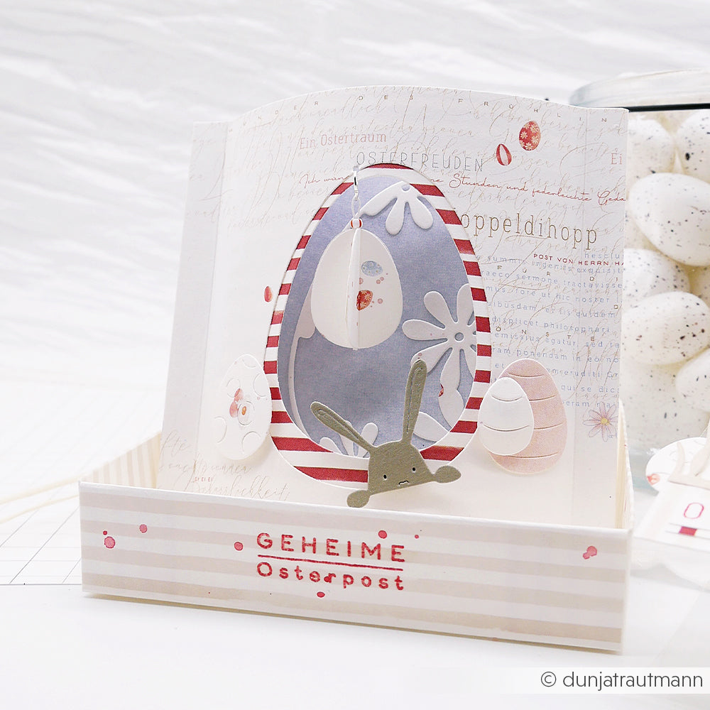 Eine handgefertigte Osterkarte von Alexandra Renke mit verzierten Eiern, einem Hasen und "GEHEIME Osterpost" auf Streifen, hergestellt mit der Motivstanze Fröhliches Eier-Set und bunten Designpapieren.