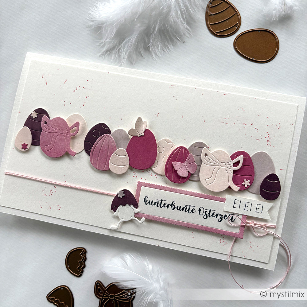 Eine handgefertigte Osterkarte von Alexandra Renke mit pastellfarbenen Ei- und Hasendesigns, deutschem Text, dekorativen Federn und charmanten Ausschnitten aus dem Motivstanze Eier-Set.