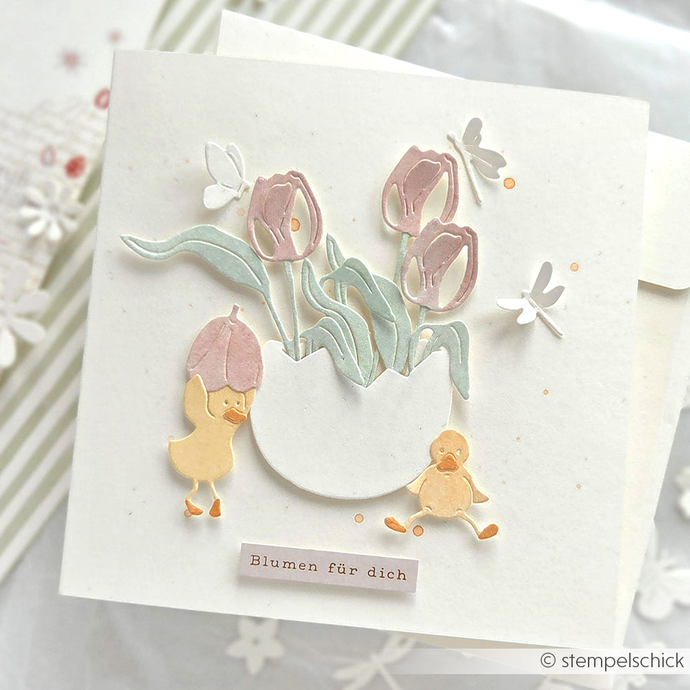 Handgemachte Karte von Alexandra Renke mit pastellfarbenen Tulpen in einer Vase, zwei Küken, Schmetterlingen und "Blumen für dich", gestaltet mit liebevoll ausgewählter Motivstanze für echten Oster-Garten-Spaß.