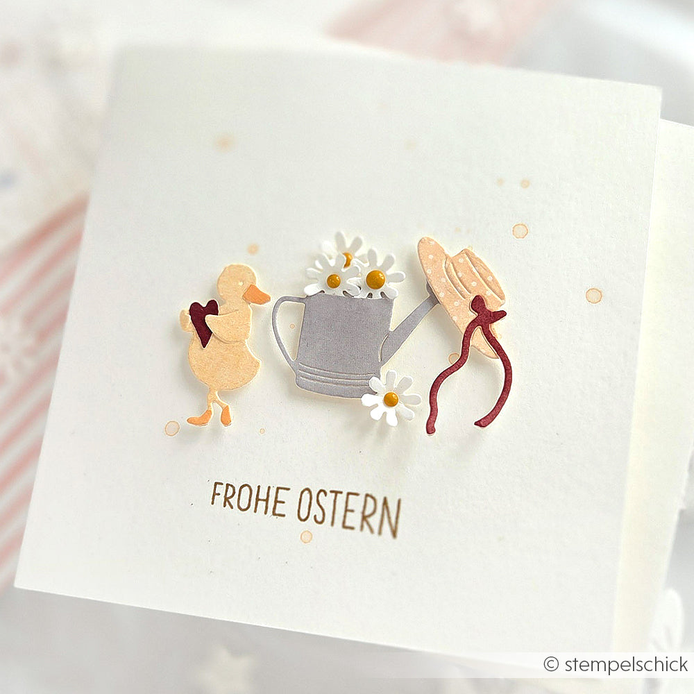 Osterkarte von Alexandra Renke mit einer Ente, einer Gießkanne mit Gänseblümchen, einem Hut und dem Text Frohe Ostern - gebastelt mit Motivstanze Kleine Eierdiebe und Designpapieren für einen reizvollen saisonalen Akzent.