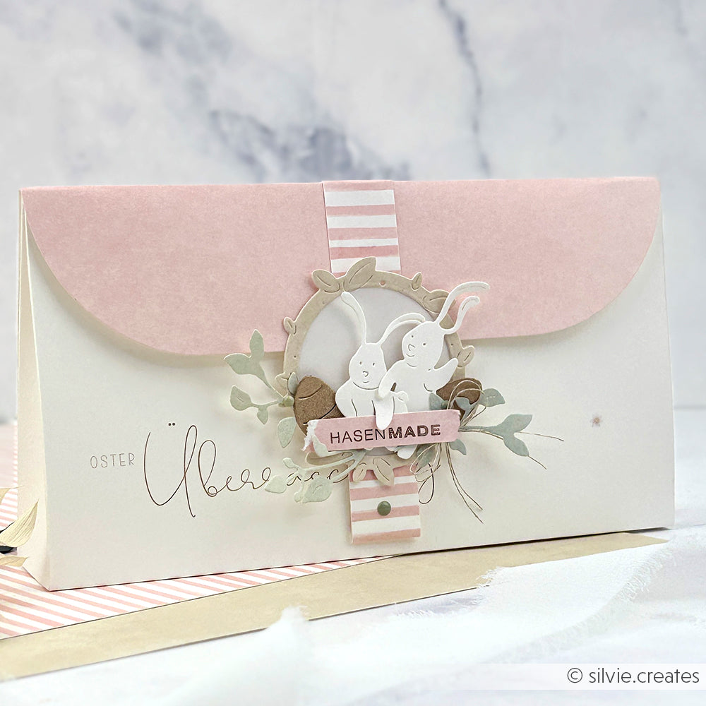 Alexandra Renke Osterkarte in Rosa und Weiß, gebastelt mit Motivstanze Ostern. Mit zwei weißen Hasenausschnitten, Blättern und dem Text "HASENMADE" - ideal für kreative Projekte mit Ihren Lieblingsdesignpapieren.