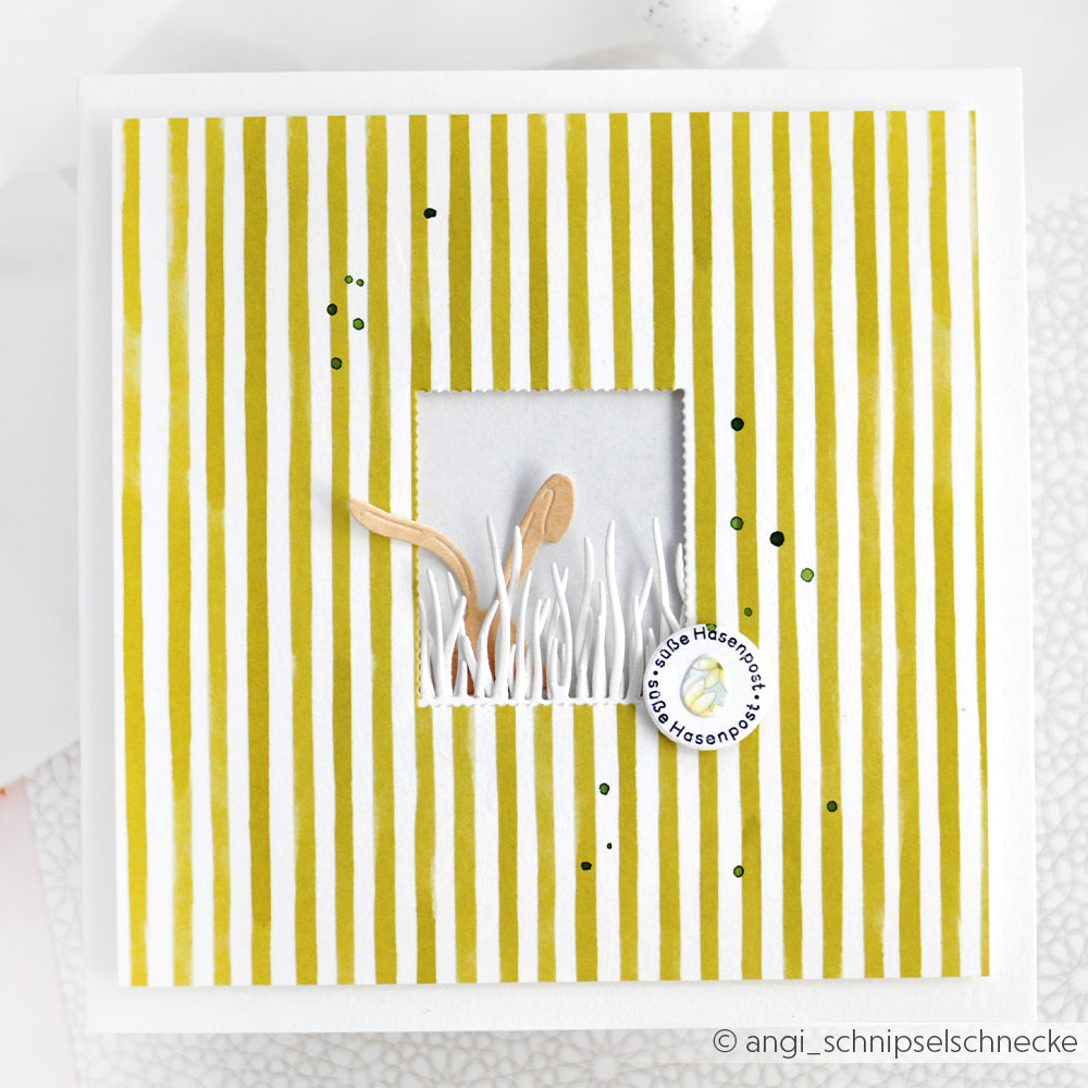 Eine quadratische Karte von Alexandra Renke mit gelben Längsstreifen, ein Fenster mit Gras und Pilzen sowie ein kleines rundes Etikett aus der Motivstanze Neugierige Häschen - perfekt für Ihre Designpapiere.