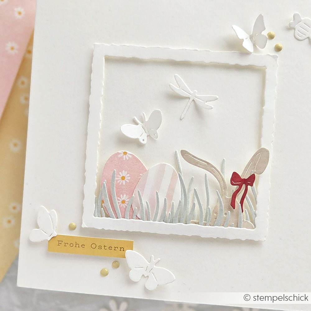 Osterkarte mit pastellfarbenen Eiern, Schmetterlingen, Libelle und dem Tag "Frohe Ostern" auf weißem Hintergrund, gestaltet mit Alexandra Renke Designpapieren und der Motivstanze Neugierige Häschen für Charme.