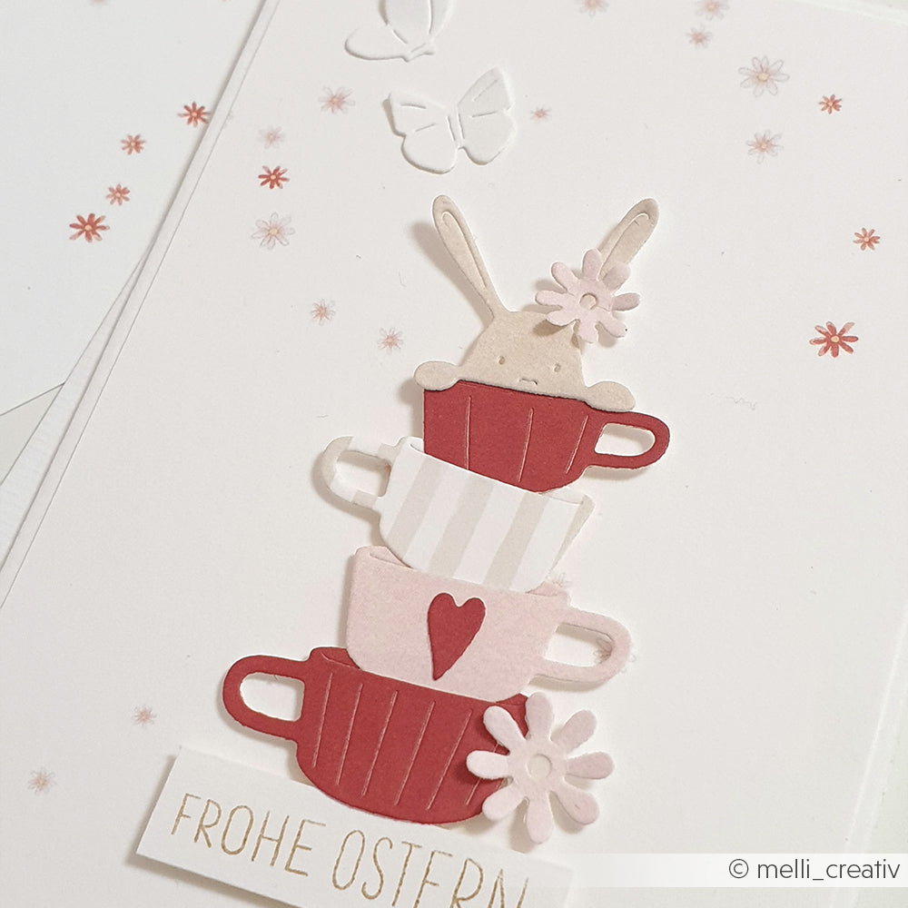 Gestapelte Teetassen mit einem Hasen, Blumen, Schmetterlingen und "Frohe Ostern" - ideal für Alexandra Renke Dies oder Motivstanze Neugierige Häschen Stanzsysteme Projekte.