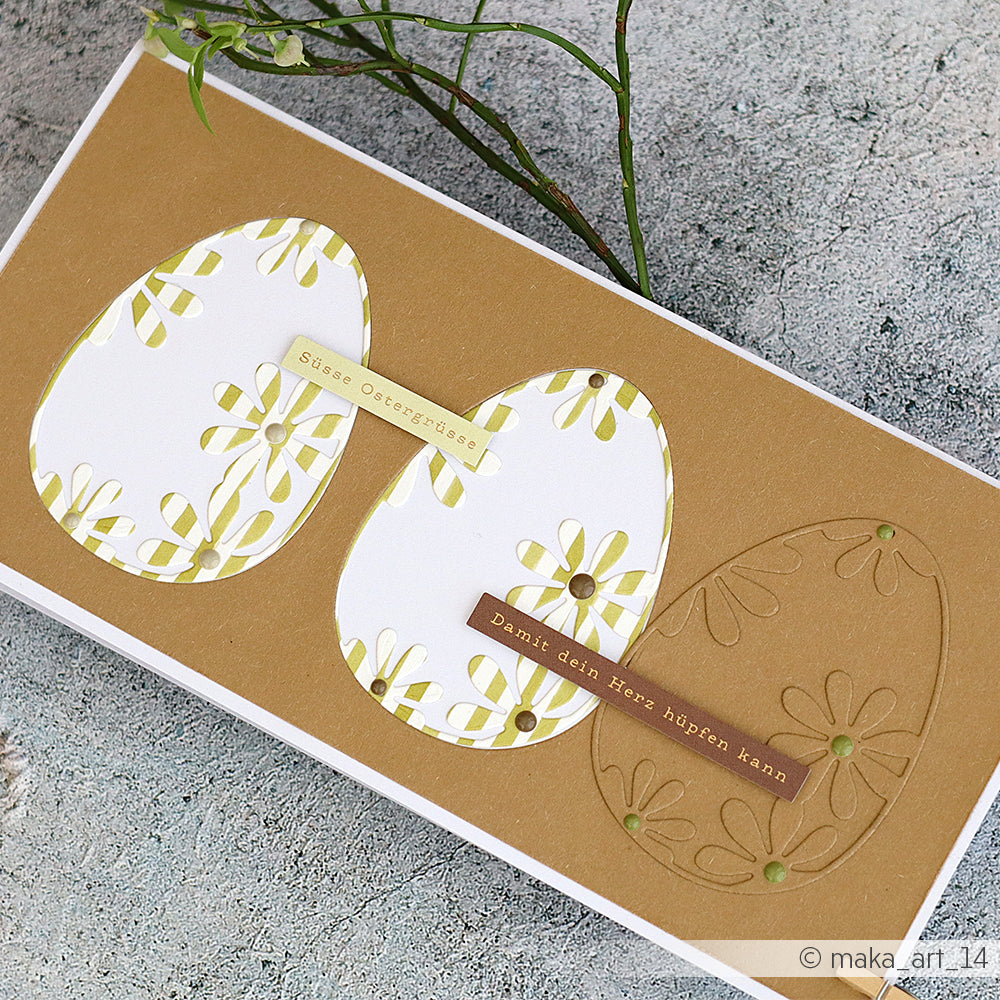 Handgemachte Osterkarte von Alexandra Renke mit zwei verzierten Eiformen, die mit Motivstanze Osterei und DieCut Systemen hergestellt wurden, sowie deutschem Text auf braunem und weißem Hintergrund.