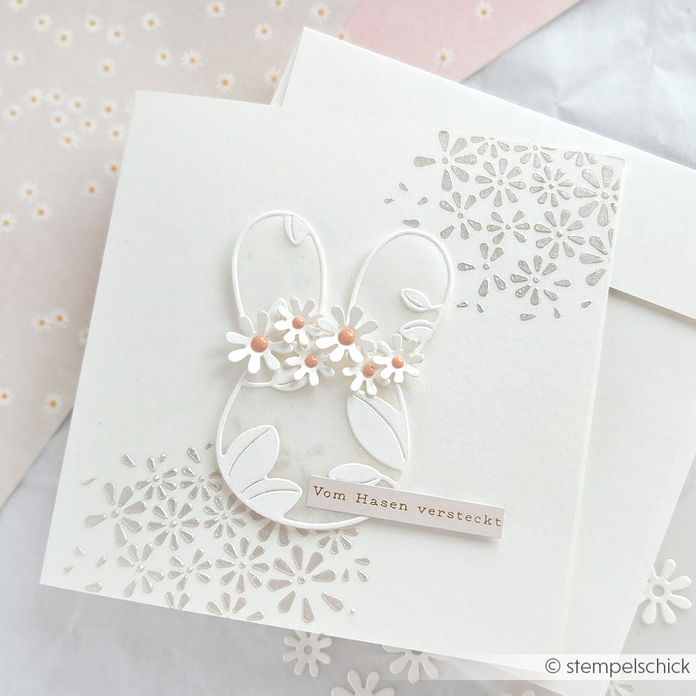 Weiße Karte mit der Alexandra Renke Motivstanze Hasenkopf, floralen Akzenten und dem Text "Vom Hasen versteckt" auf charmantem Alexandra Renke Designpapier.