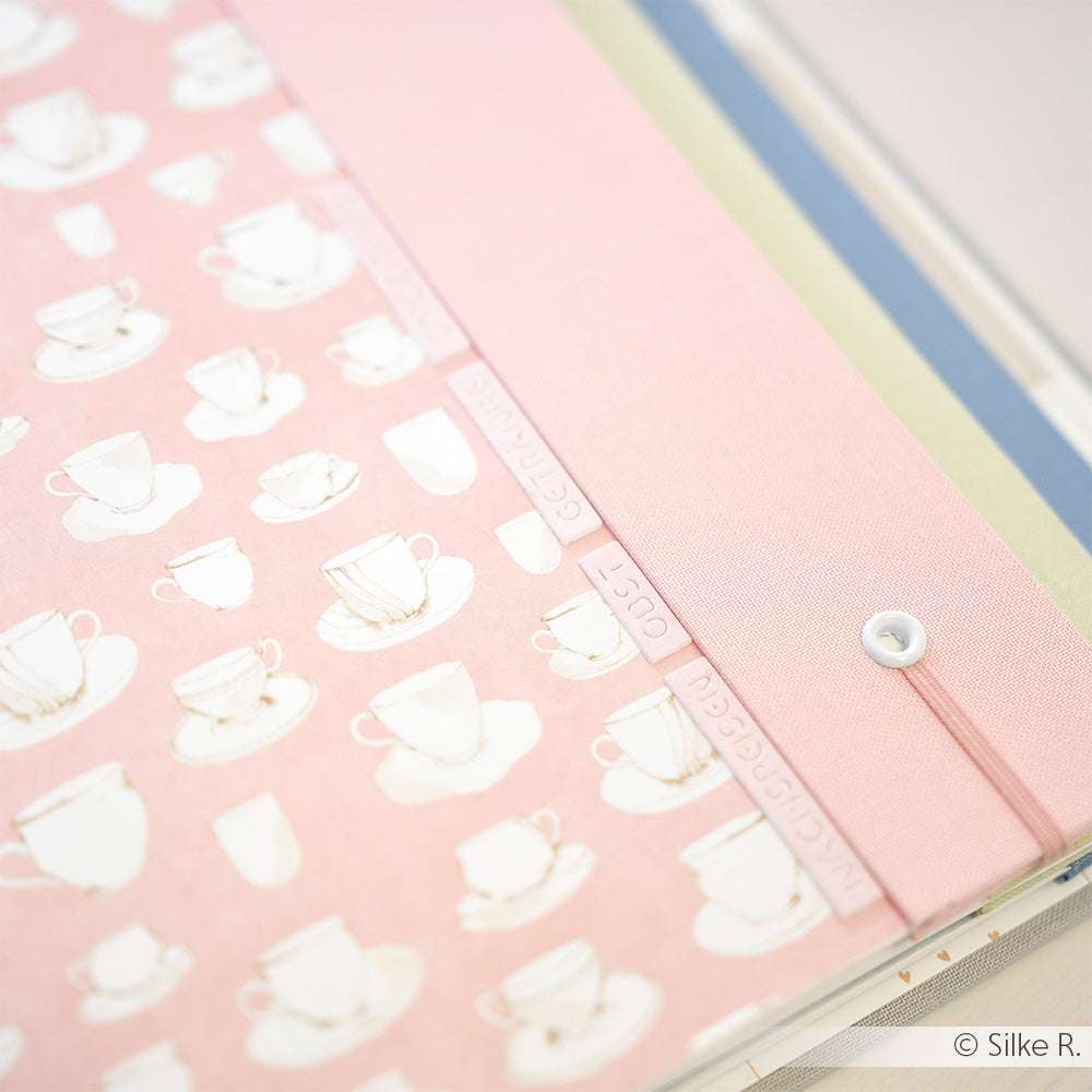 Rosa Mappe von Alexandra Renke mit Teetassenmuster, Knopfverschluss und pastellfarbenen Trennwänden - ideal für Papierprojekte oder zur Aufbewahrung Ihres Lieblingsdesignpapiers.