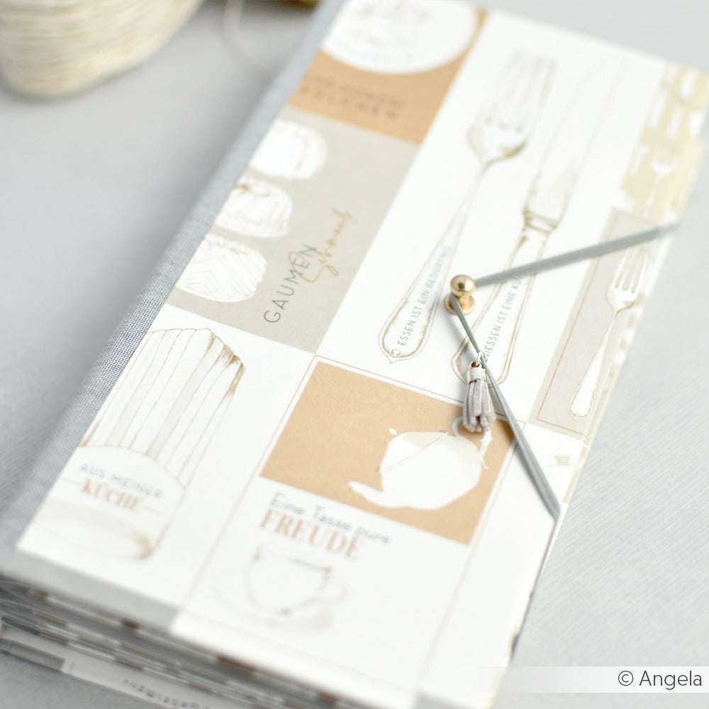 Das Alexandra Renke Rezeptbuch im beige-weißen Küchenutensilien-Design ist ideal für Papierprojekte oder die Aufbewahrung von Designpapier. Es schließt sicher mit einer elastischen Schnur und Wulst.