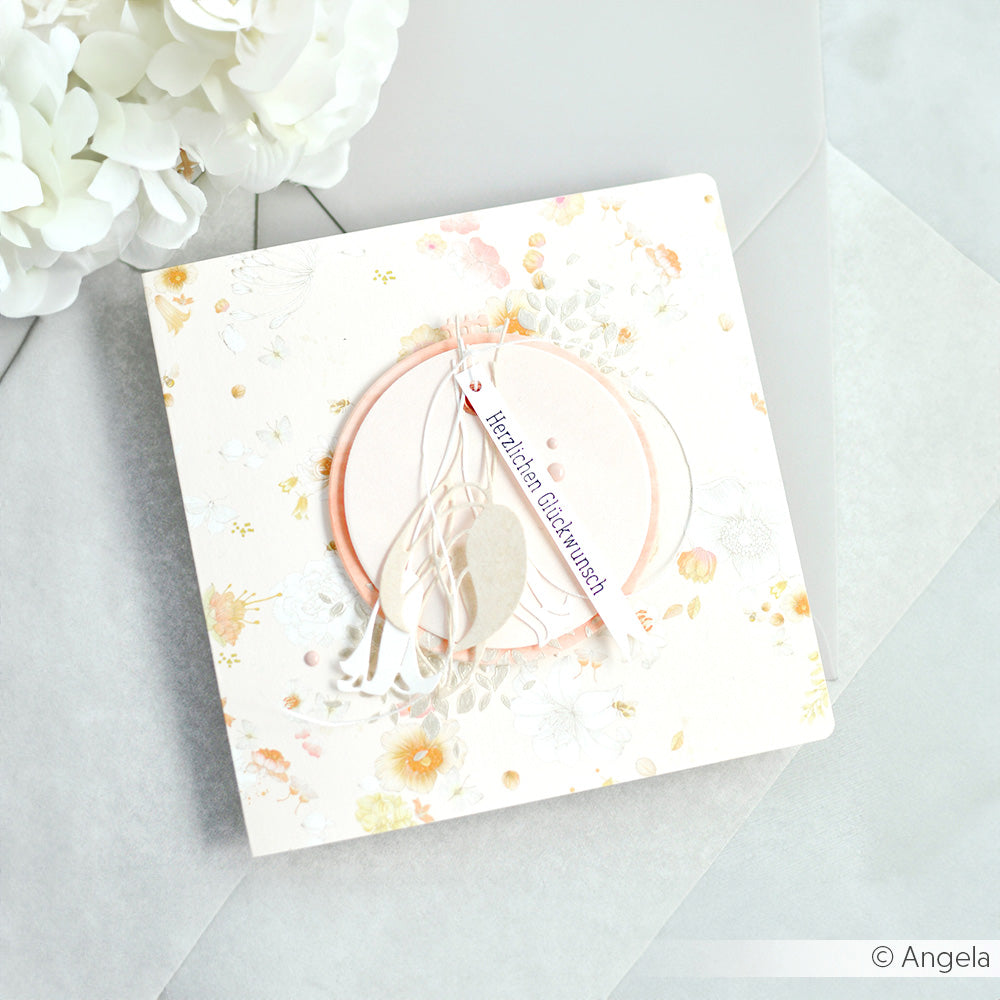 Quadratische Blumengrußkarte von Alexandra Renke, gestaltet mit geschichteten Kreisen, zarten Federn und einem "Herzlichen Glückwunsch"-Tag auf hellem Hintergrund.