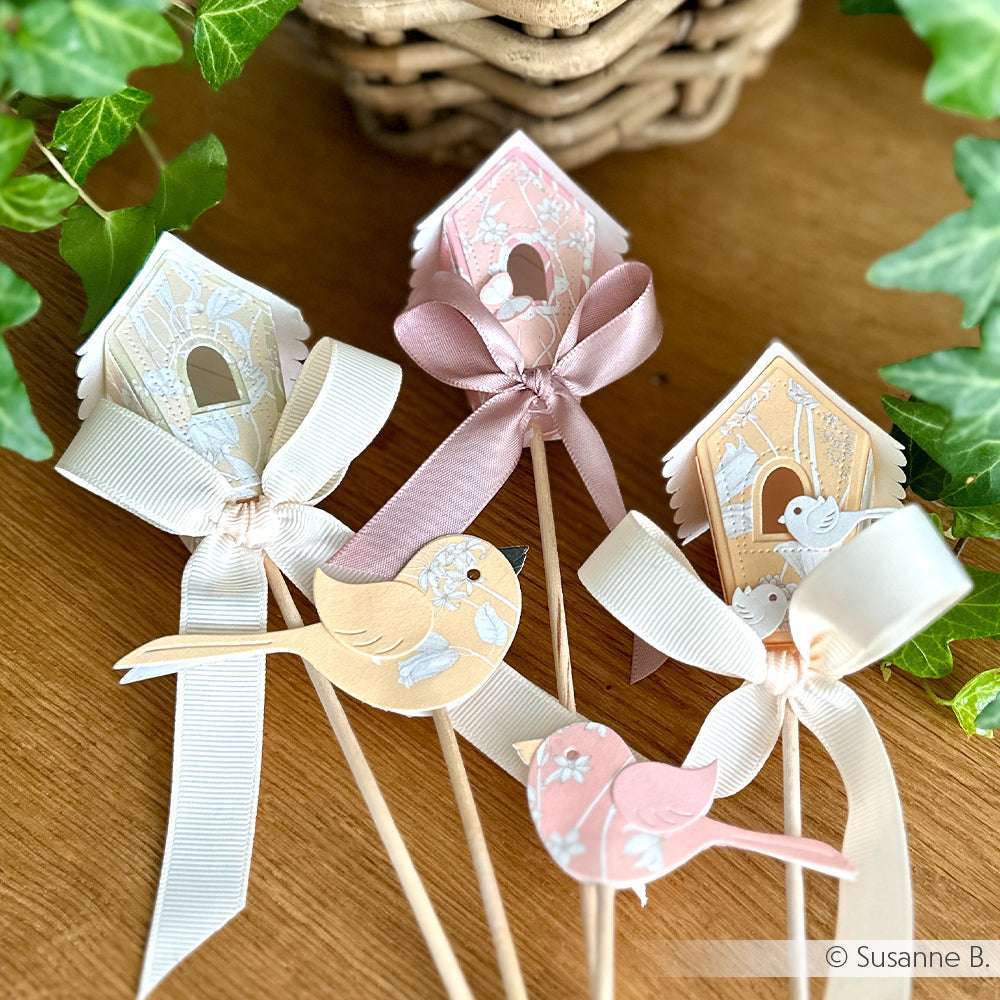 Vier Deko-Sticks von Alexandra Renke mit pastellfarbenen Vogelhäuschen, Bändern und Vogelausschnitten - ideal für Papierprojekte oder als charmante Dekoration für die Weiße Blumenvariation.