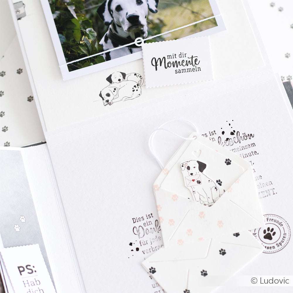 Das offene Scrapbook von Alexandra Renke zeigt Dalmatiner-Fotos, Pfotenabdrücke und illustrierte Briefumschläge auf weißen Seiten - eine ideale Inspiration für Papierprojekte oder die Gestaltung mit eigenem Designpapier.