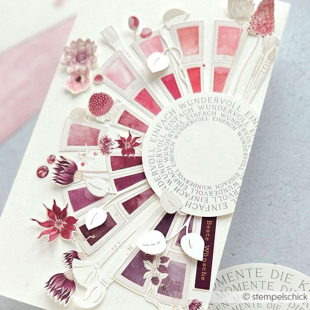 Fächerförmiges Designpapier von Alexandra Renke mit rosafarbenen und lilafarbenen Blumen, Farbklecksen und deutschem Text auf weißem Grund - ideal für Papierprojekte oder als Muster für den Farbkartenkreis Beerentöne.