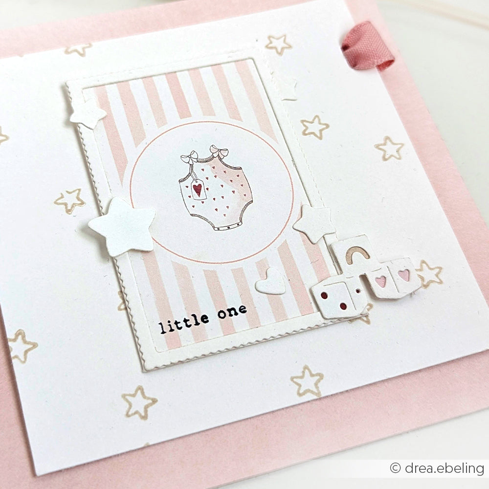Eine rosa-weiße Babykarte von Alexandra Renke mit einem Strampler, Sternen und einem "Kleinen" - eine bezaubernde Grußkartenidee mit Ihrem Lieblingsdesignpapier.