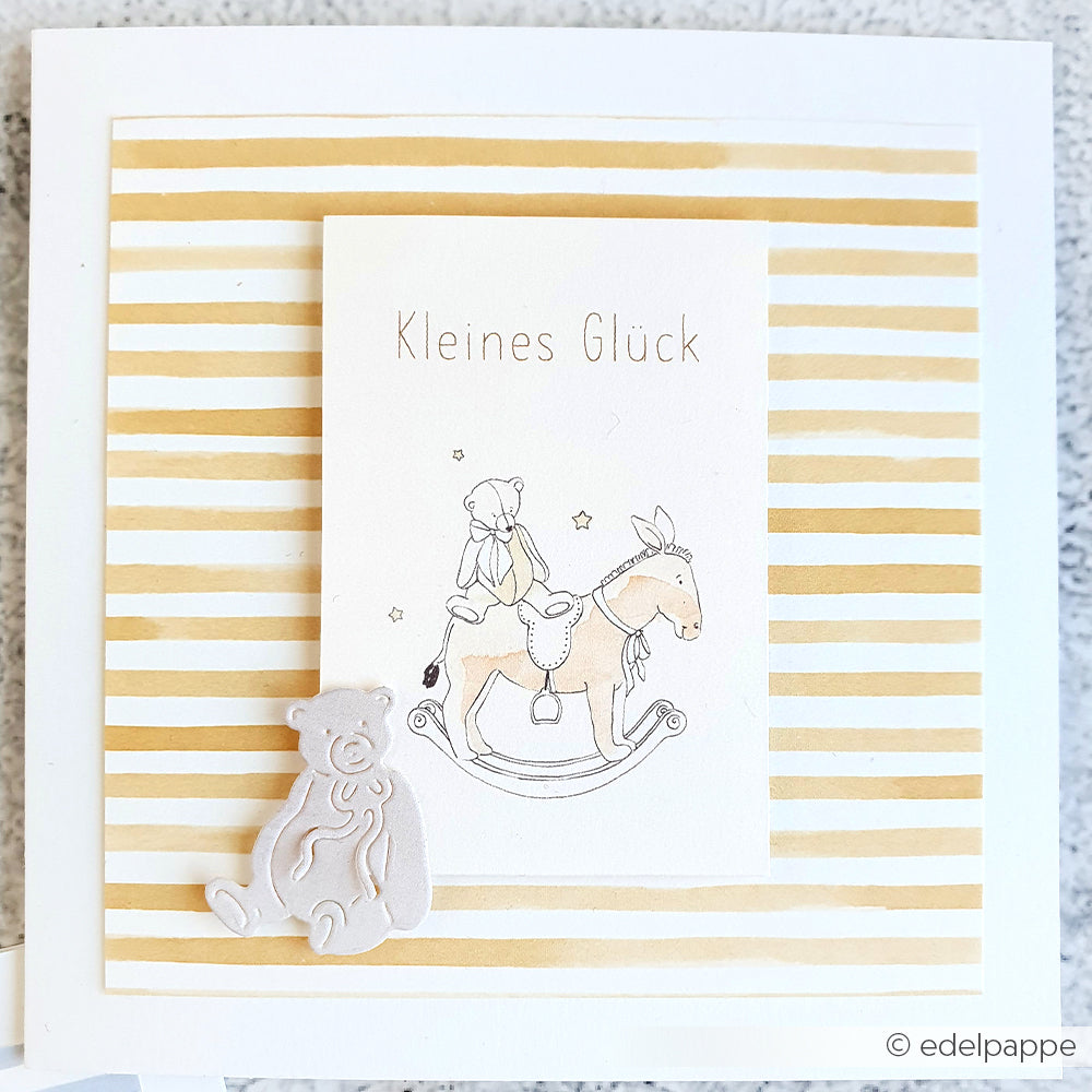Handgefertigte Grußkarten von Alexandra Renke mit Goldstreifen, einem Teddybär und einem Bären auf einem Schaukelpferd mit "Kleines Glück". Ideal für besondere Papierprojekte oder als einzigartige Karte aus hochwertigem Designpapier gefertigt.